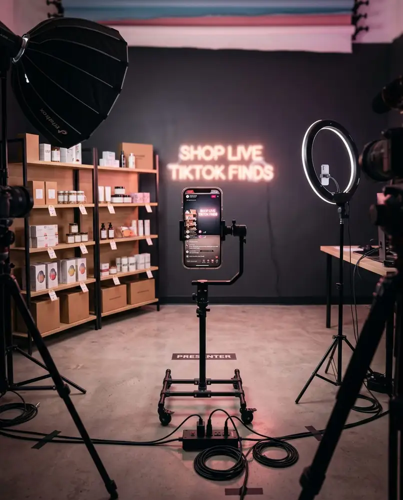 A multi-camera live-shopping studio set with a ring light, tripod-mounted phone rig and product shelving
